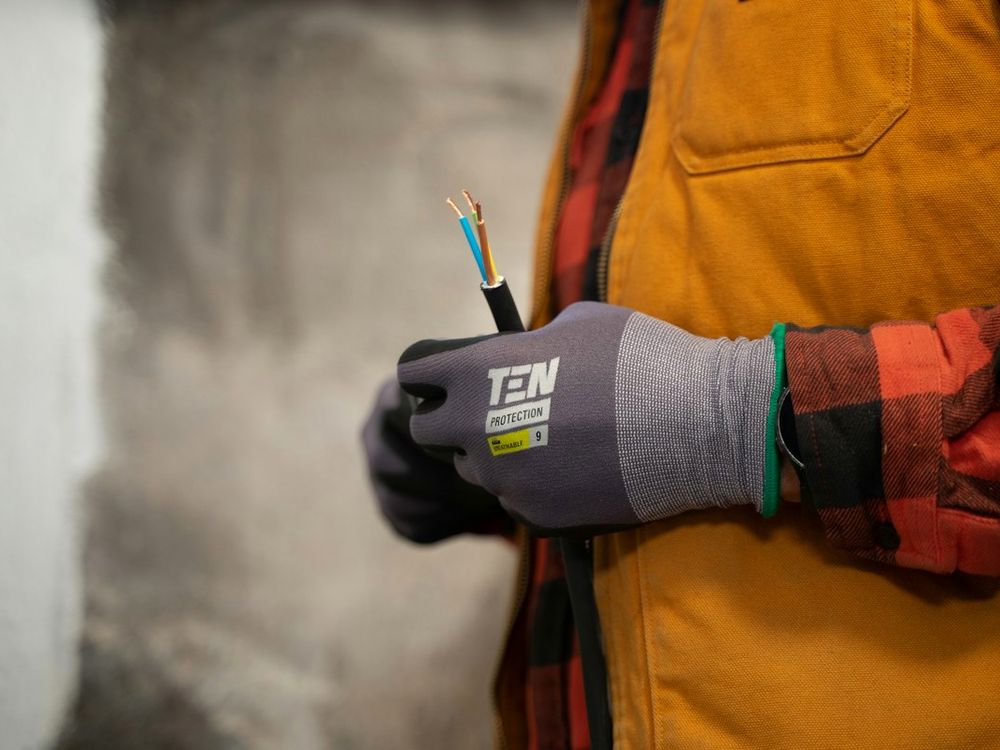 Électricien tenant des conducteurs électriques avec des gants de protection